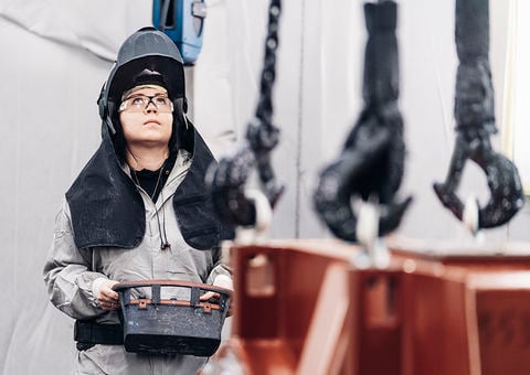 Woman operates overhead crane.